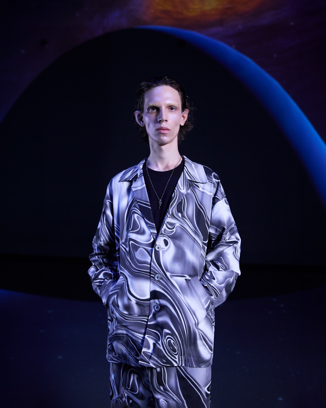 Origin campaign, silver marble-print suit against planet